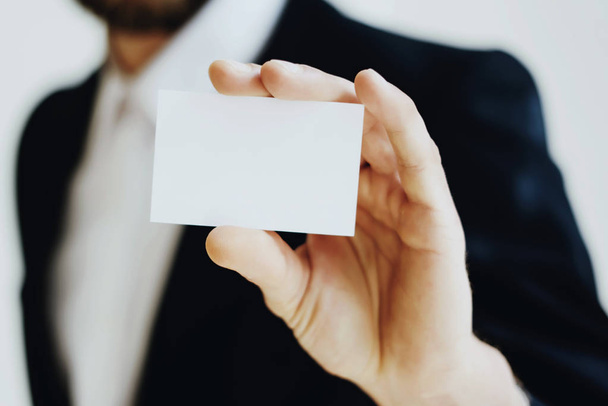 Businessman holding in hand clean white business card.Horizontal mock up, blurred background. - Foto, Bild
