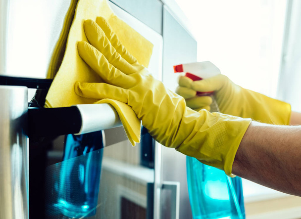 Man's hand in glove with rag cleaning oven - Photo, Image
