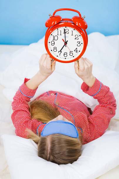 Στον ύπνο γυναίκα που φοράει πιτζάμες κρατώντας ρολόι - Φωτογραφία, εικόνα