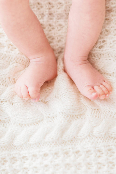 Baby's feet on white knitted background. Little child's bare feet. Cozy morning bedtime at home. Place for text. - 写真・画像
