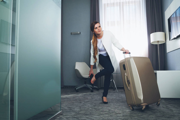 Woman pulling suitcase in modern hotel room - Fotoğraf, Görsel