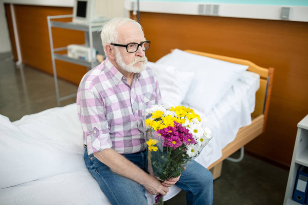 Senior man with flowers in hospital  - Photo, Image