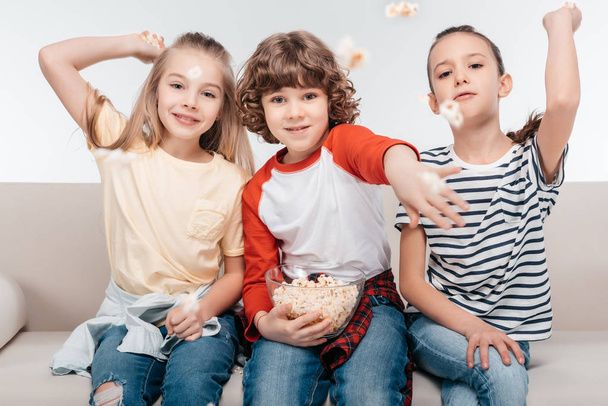 Cute children on couch with popcorn - Foto, Imagen