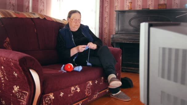 Πορτρέτο του ένα βλέποντας τηλεόραση ανώτερων γυναίκα πλέκει κάλτσες μαλλιού - Πλάνα, βίντεο