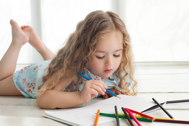 Милая маленькая девочка рисует с красочными карандашами на бумаге. Претти
  - Фото, изображение
