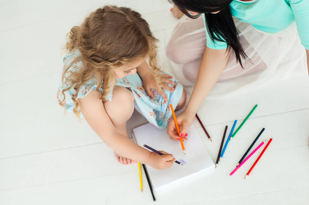 Little cute daughter and her mother drawing with colorful pencil - 写真・画像