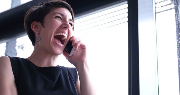 businesswoman speaking on phone beside window of modern office   - Zdjęcie, obraz