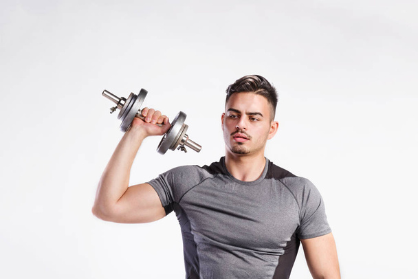 Fitness man holding dumbbell, working out, studio shot. - Valokuva, kuva