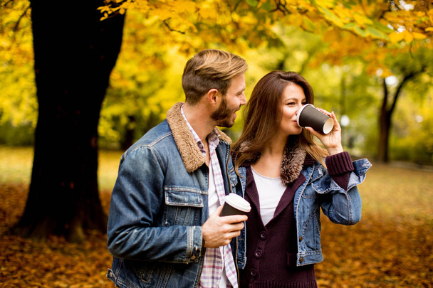 Young couple in the autumn park with coffee - Valokuva, kuva