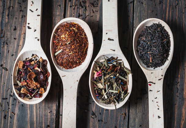 Различные виды чая в деревянных ложках на деревянном столе
 - Фото, изображение