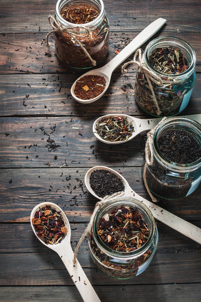 Diferentes tipos de té en tarro y cucharas de madera en mesa de madera
 - Foto, Imagen