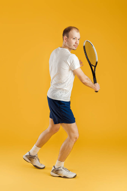 young tennis player plays tennis on yellow background - Foto, Imagen