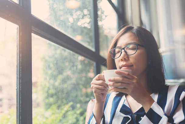 Donna asiatica rilassata in possesso di una tazza di caffè caldo. Occhiale di felicità
 - Foto, immagini