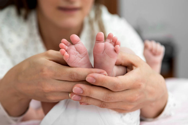 Las manos de los padres sujetan suavemente los pies del bebé desde abajo
 - Foto, Imagen