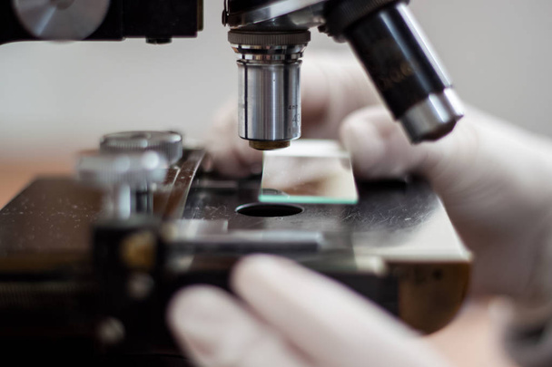 Un giovane medico studia al microscopio, tenendo con attenzione una copia
 - Foto, immagini