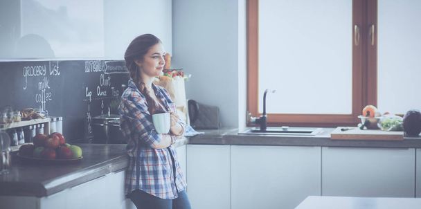 Happy woman drinking tea in the kitchen at home - Valokuva, kuva