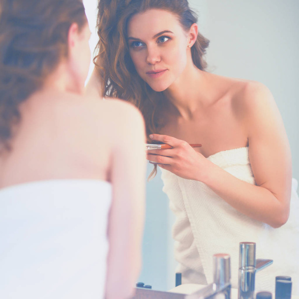 fiatal nő néz a tükörbe, és smink fel - Fotó, kép