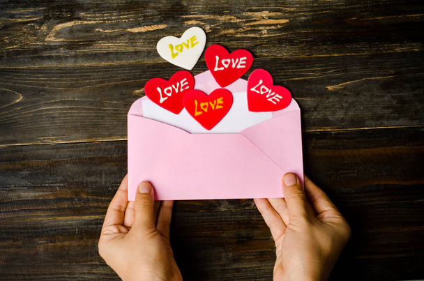 Roze envelop en rood hart op houten achtergrond - Foto, afbeelding