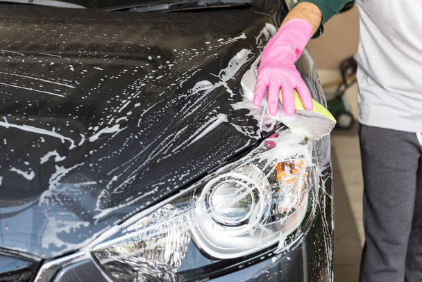 Hand hold sponge over the car for washing - 写真・画像