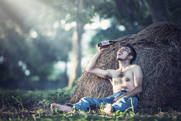 Alcohol addicted man sitting alone with alcohol bottle - Foto, Bild