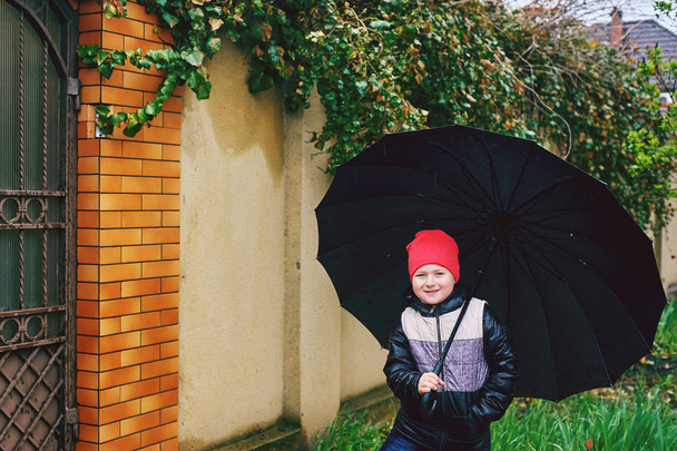 Criança alegre brincando com um guarda-chuva enquanto caminha na chuva
 - Foto, Imagem