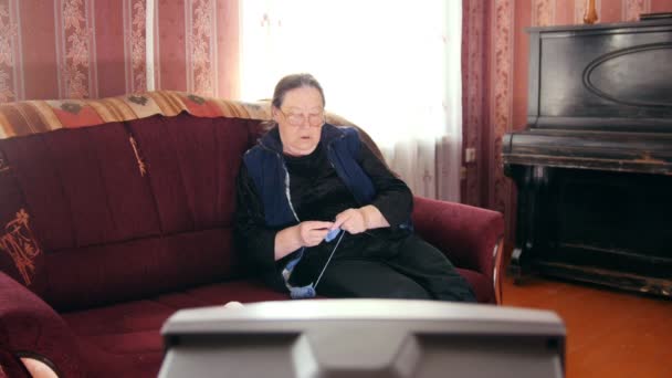 Ηλικιωμένη κυρία στο σπίτι - ανώτερος γυναίκα βλέποντας τηλεόραση και πλεκτά μαλλί κάλτσες - Πλάνα, βίντεο