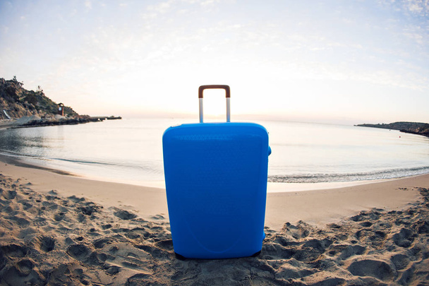 Viajes, vacaciones y concepto de vacaciones - maleta azul en la playa
. - Foto, imagen