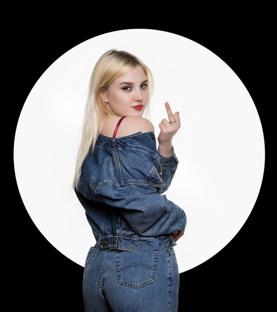 back view of young woman in denim jaket and jeans show middle finger, fuck you off sign on white background. indecent lifestyle concept - Foto, Bild