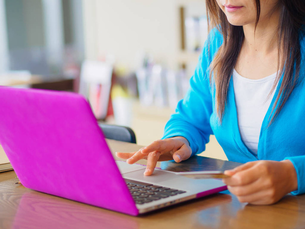 Pretty Young womans hands holding a credit card and using laptop computer for online shopping - Photo, Image