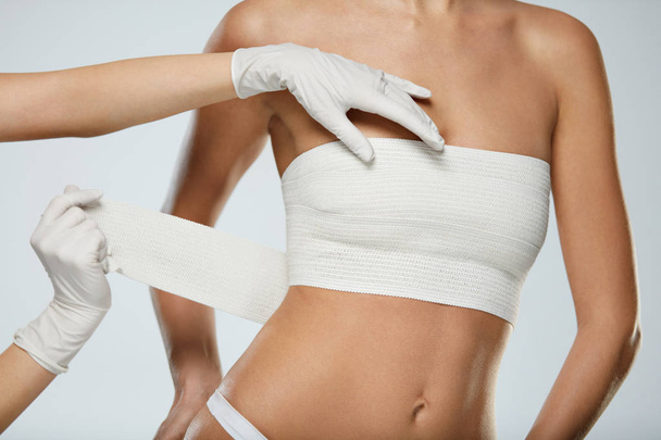 Plastic Surgery. Doctor Hands Wrapping Female Breast In Bandage - Valokuva, kuva