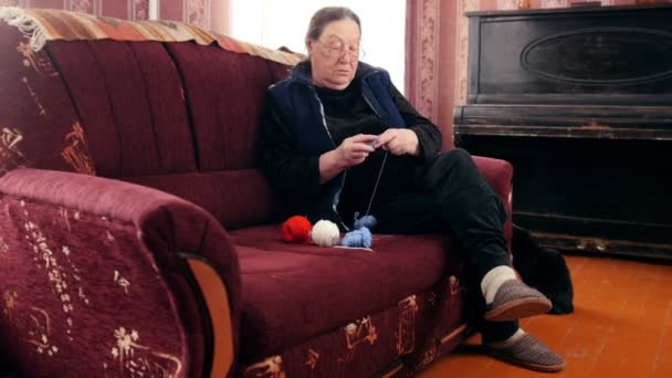 Senior dame zit op de Bank en breit wollen sokken - gepensioneerden hobby thuis, schuifregelaar schot - Video