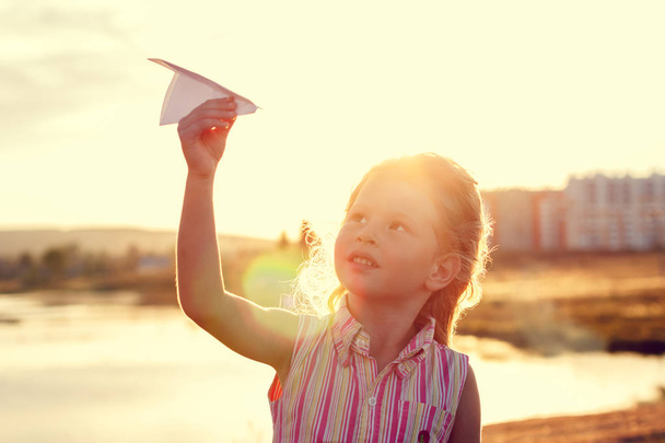 Ευτυχισμένος κορίτσι παίζει με ένα αεροπλάνο χαρτί - Φωτογραφία, εικόνα