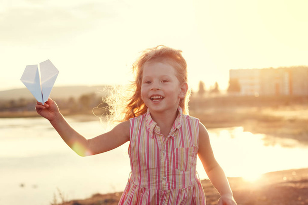 Menina feliz brincando com um avião de papel
 - Foto, Imagem