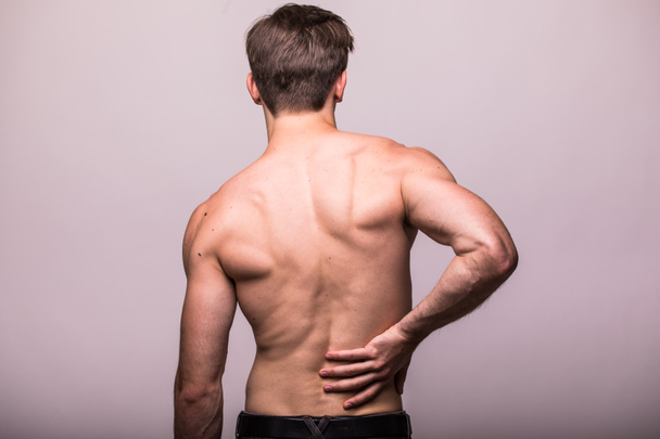 Hombre frotando su dolorosa espalda en gris. Alivio del dolor, concepto quiropráctico
 - Foto, Imagen