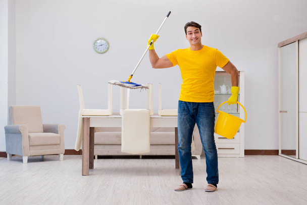 Ο άντρας καθαρίζει το σπίτι βοηθώντας τη γυναίκα του. - Φωτογραφία, εικόνα