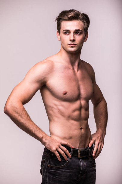 Atleta saludable joven musculoso sobre un fondo gris
 - Foto, Imagen