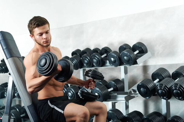 Handsome young athlete working out at the gym - 写真・画像