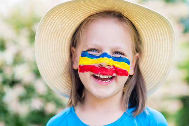 Laughing little girl in straw hat with painted face having fun.  - Foto, immagini