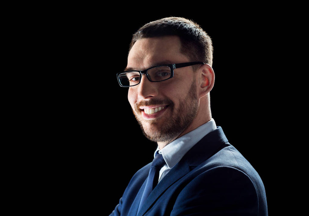 smiling businessman in glasses over black - Foto, Imagen