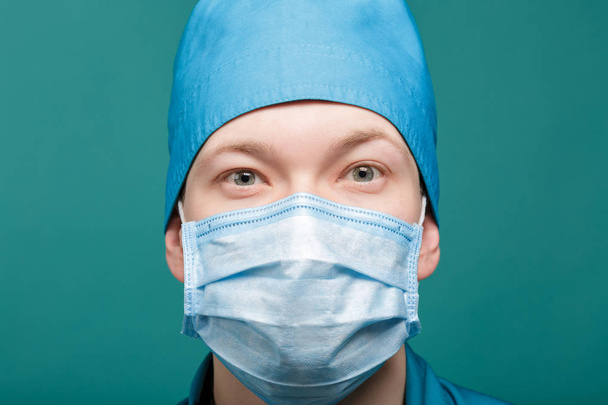 male surgeon in mask looking at camera on blue background, close up - Foto, Imagen