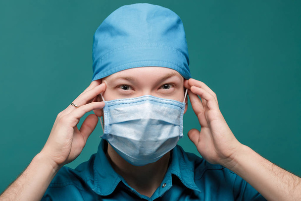tired male surgeon in mask on blue background, close up - Fotó, kép