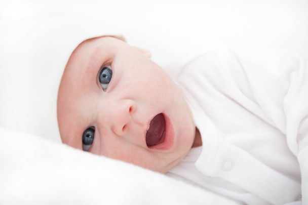 νεογέννητο μωρό σε λευκό, χασμουρητά, κοιτάζοντας την κάμερα - Φωτογραφία, εικόνα