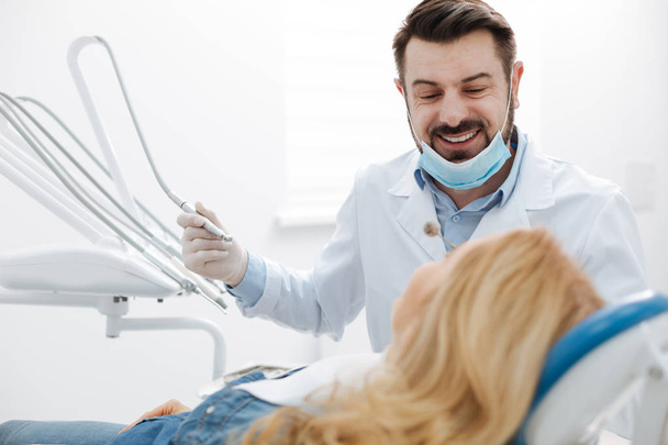 Handsome friendly dentist calming his patient - Foto, afbeelding