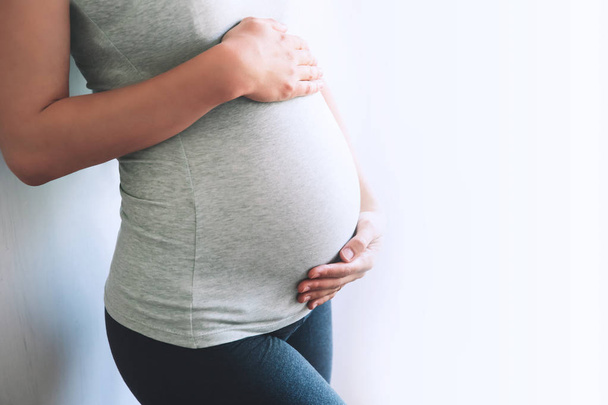 Close-up pregnant woman on a white background. - Фото, зображення
