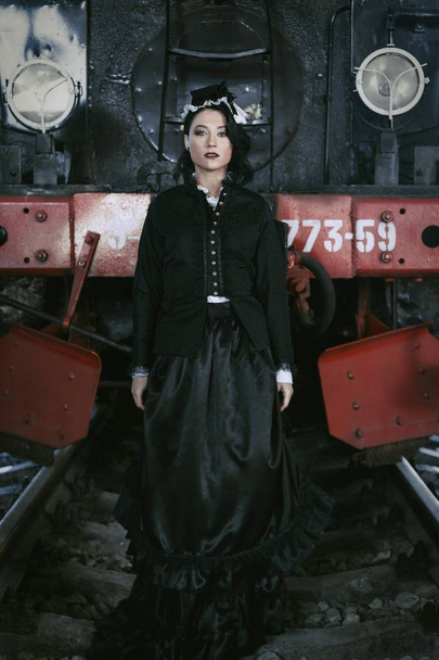 woman in vintage dress near steam locomotive - 写真・画像
