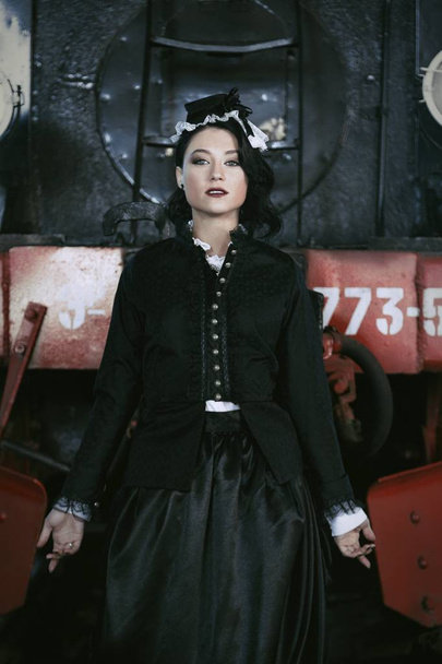 woman in vintage dress near steam locomotive - Foto, afbeelding