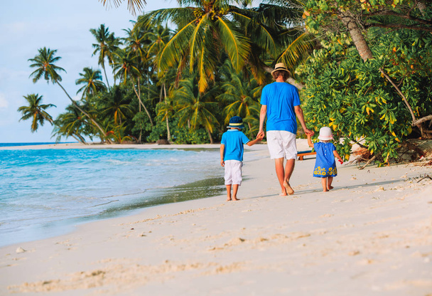 father and two kids walking on beach - Фото, изображение
