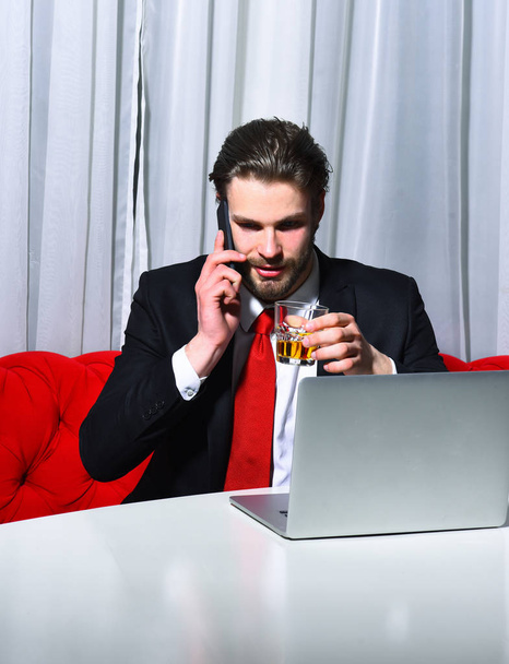 bearded man, businessman holding glass of whiskey works at laptop - Foto, Imagem
