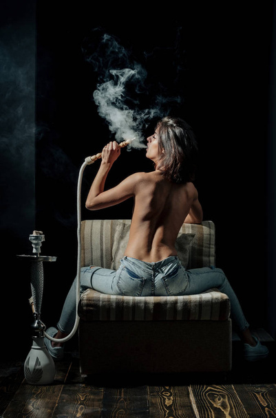 sexy girl with naked body smoking hookah in jeans - 写真・画像