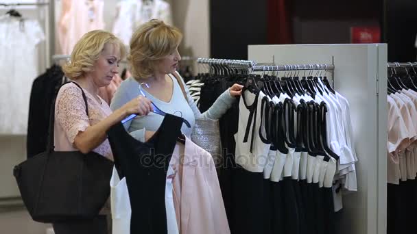 Twee senoir vrouwen in boutique kiezen jurk. - Video